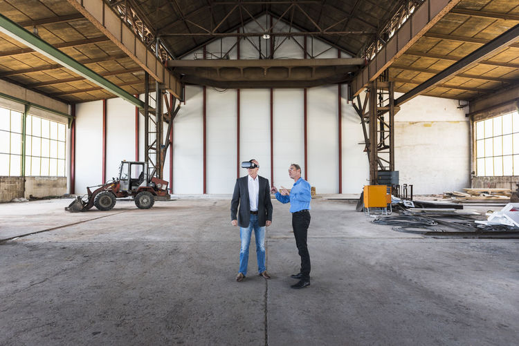 Two businessmen with vr glasses talking in old industrial hall