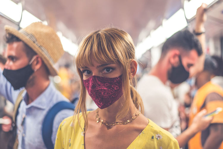 Portrait of woman wearing mask standing in bus