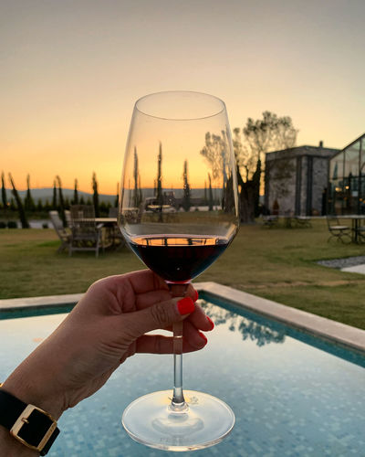 Sunset at wine tasting in urla, turkey. female hand is holding a glass of red wine