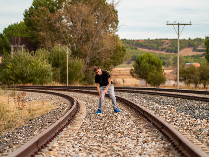Full length of teenage boy standing on railroad track