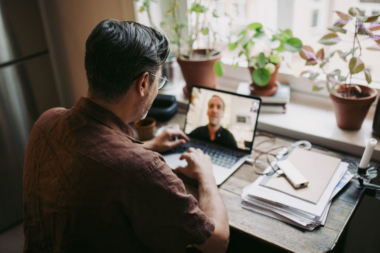 Male entrepreneur discussing with colleague on video call at home office