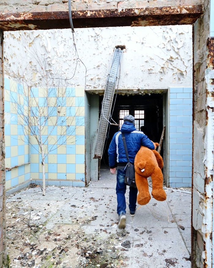 Rear view of man with toy walking towards abandoned house