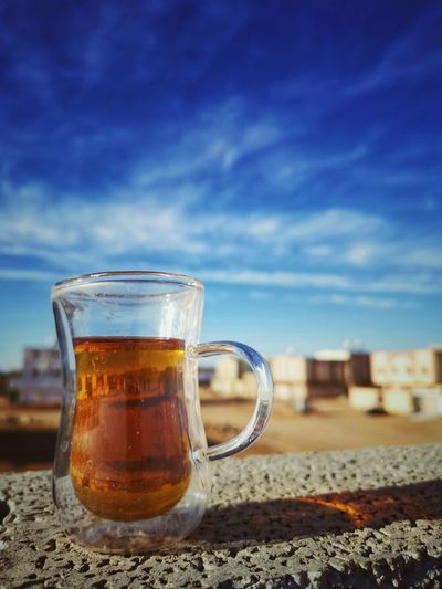 Close-up of beer glass on beach against sky