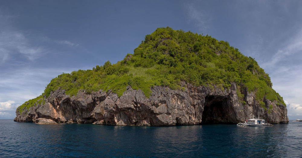 Panoramic view of rock formation in sea against sky
