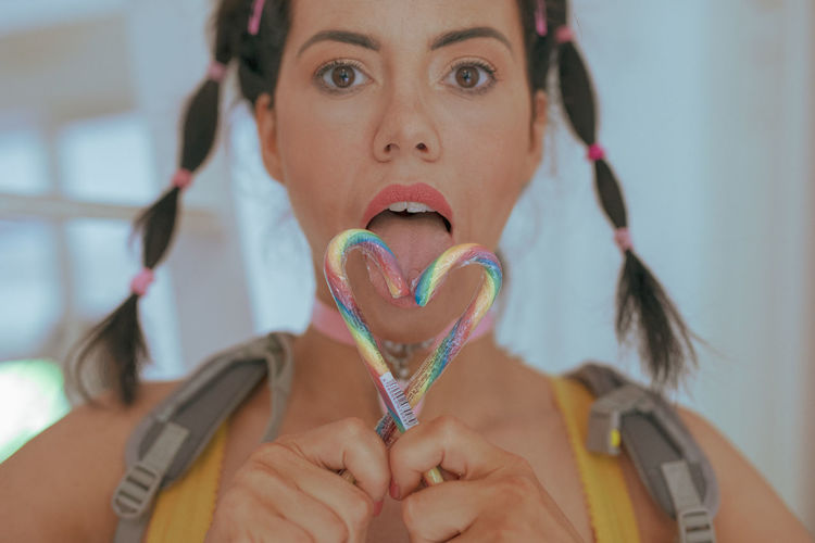 Close-up portrait of woman holding candy canes at home