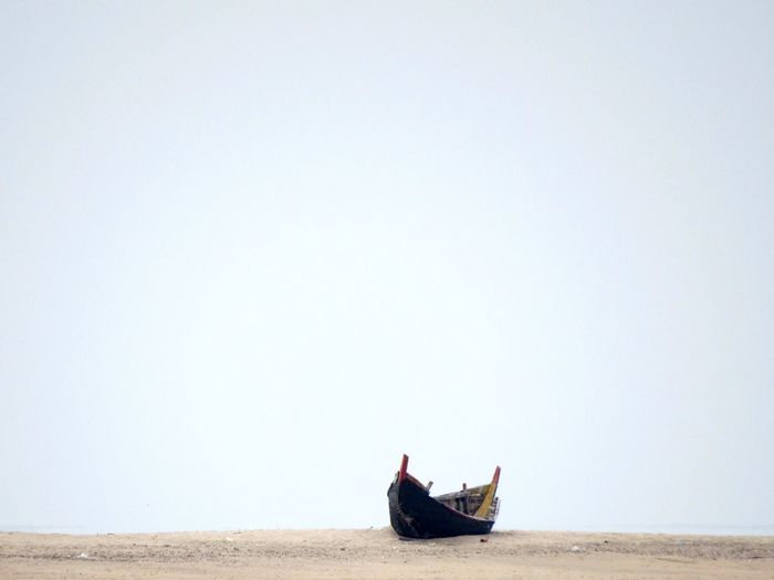 Abandoned boat on shore against clear sky