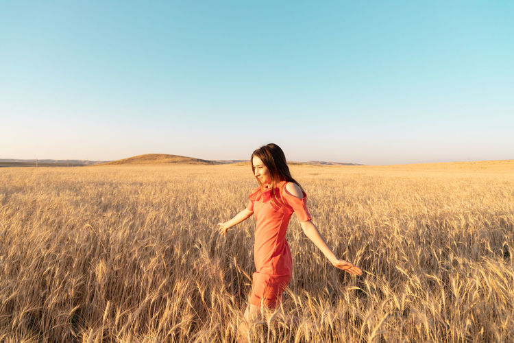 Young woman in the wheat field. connecting with nature concept. moments of joy. arms out to the side