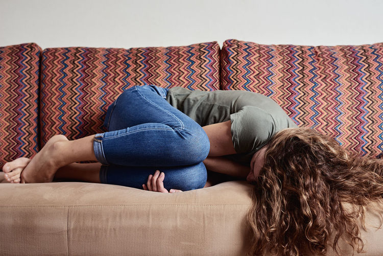 Woman lying on sofa, suffering from abdominal pain