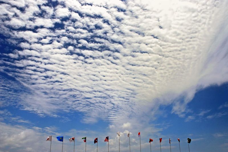 Various flags against cloudy sky