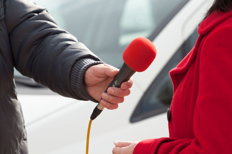 Cropped hand of reporter holding microphone