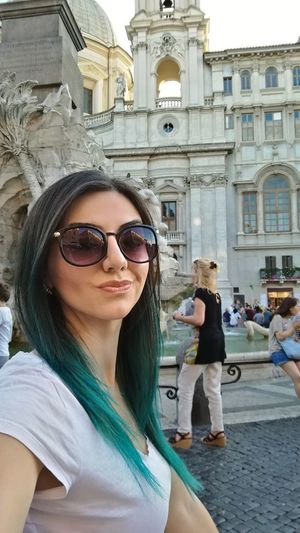 Young woman wearing sunglasses in city against sky