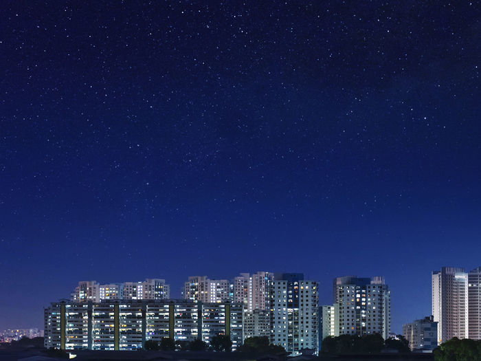 Illuminated cityscape against blue sky