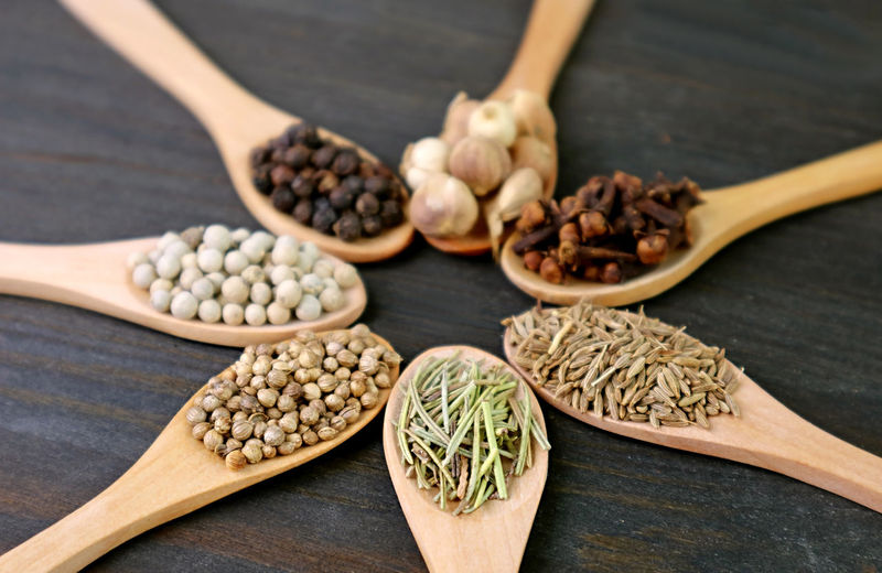 
closeup of assorted aromatic spices in wooden spoons with selective focus
