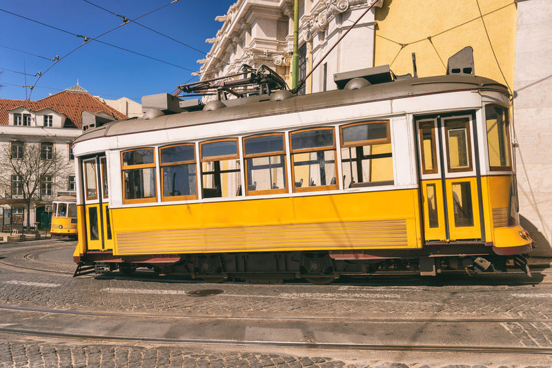 Yellow train on railroad track by buildings in city