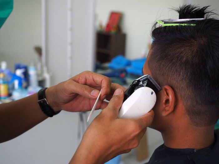 Cropped hands of hairdresser cutting man hair