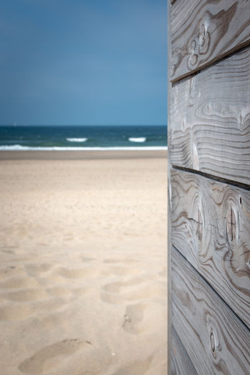 Summertime picture with gray patina wood in front of sandy beach and blue sky
