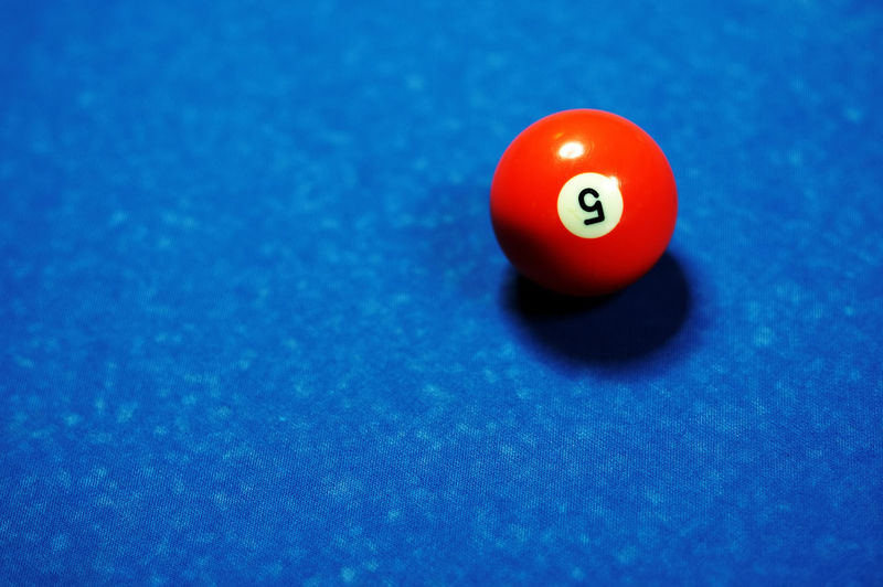 High angle view of number 5 pool ball on blue table