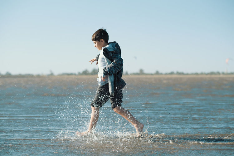 Side view of boy running in sea