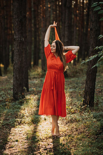 Young woman using mobile phone while standing in forest