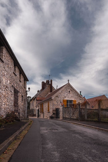 Empty road amidst buildings against sky