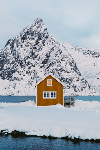 House on snowcapped mountain against sky