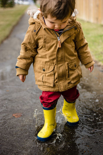 Toddler playing in puddle on sidewalk in city