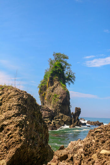 Rock formation on beach against sky
