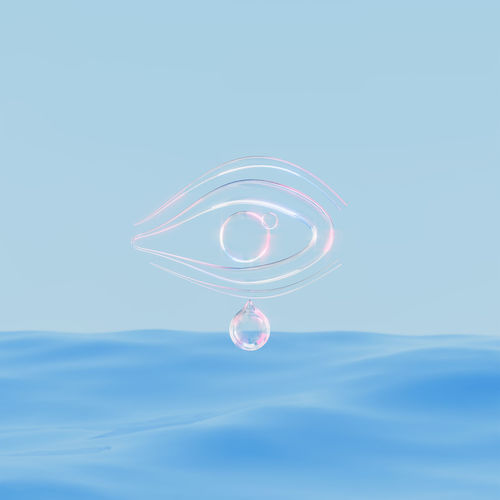 Abstract glass or crystal transparent eye with tear hanging on blue sea. ocean background. 