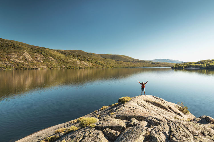 Man with arms open near a lake