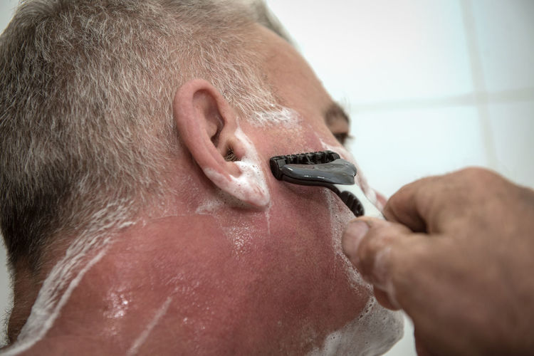 Close-up of man shaving