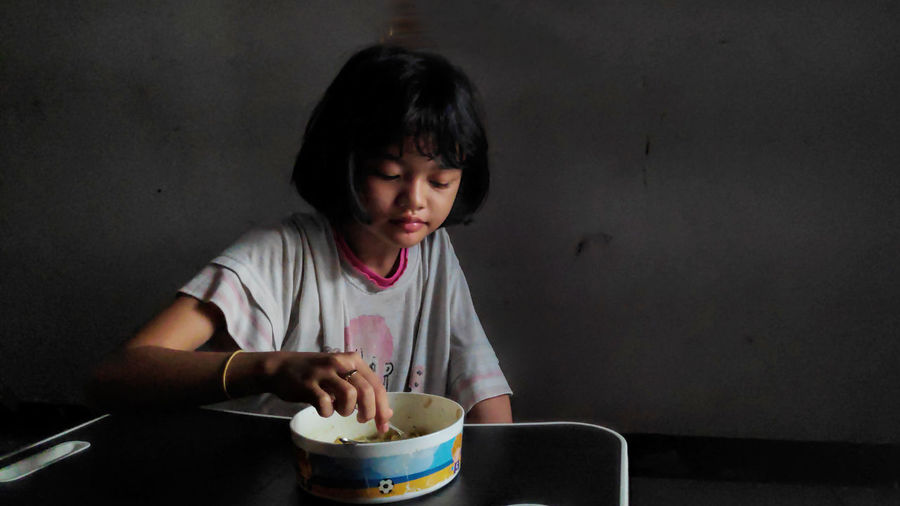  little asian girl enjoy eating with some noodles on a bowl in lunch time, delicious face.
