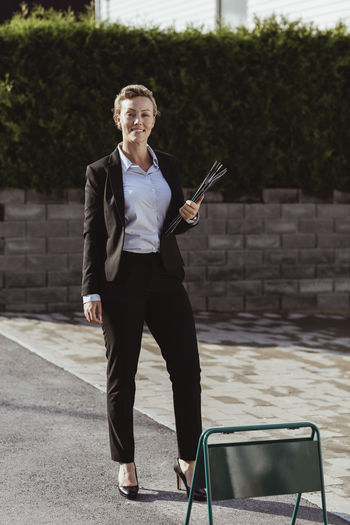 Portrait of smiling female real estate agent standing at sidewalk