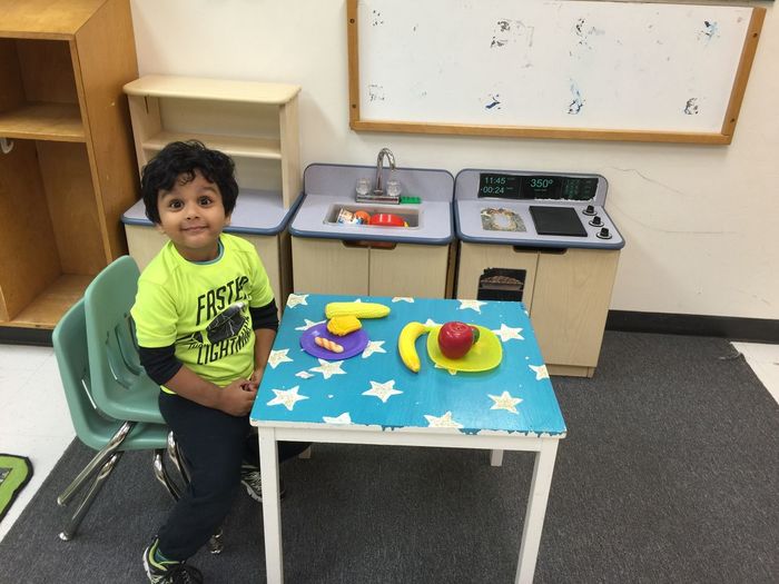 High angle view of boy sitting on chair by table at kindergarten