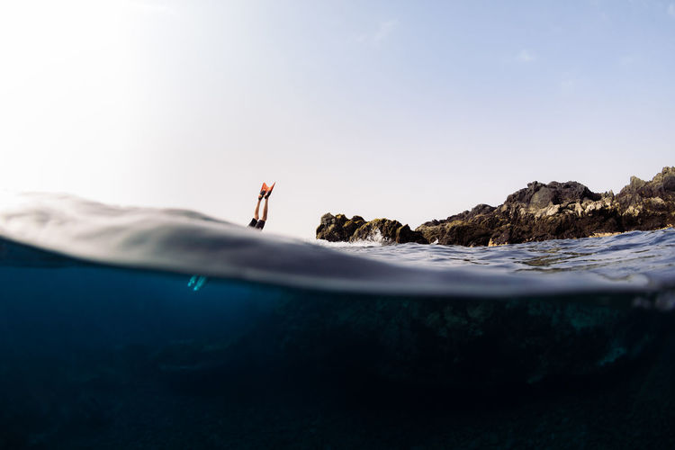 Young adult jumping into sea water in summer