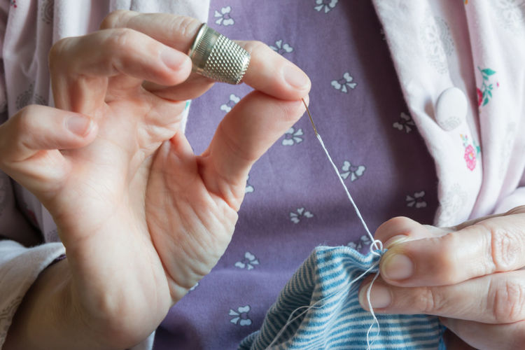 Midsection of woman stitching textile 
