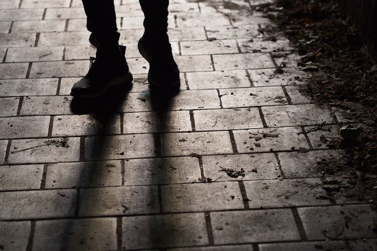 Low section of man walking on paved footpath