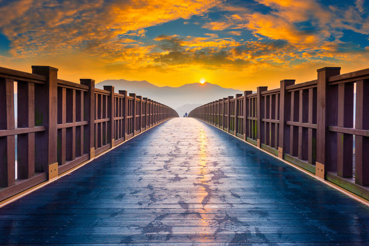 Footbridge against sky during sunset
