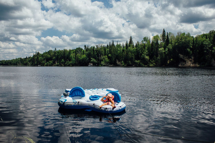 Young child laying on floating raft on river in northern ontario