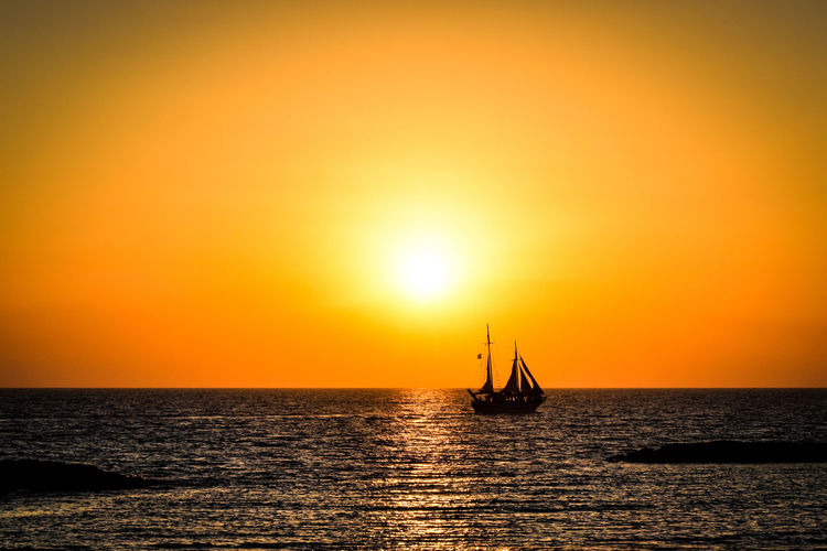 Silhouette of boat in sea during sunset