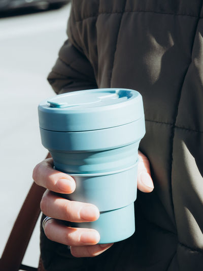 Female hands hold blue reusable coffee mug. sustainable lifestyle. eco friendly concept.