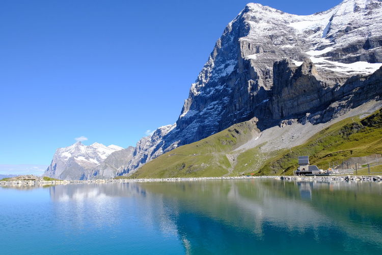 Scenic view of lake and snowcapped mountains against blue sky