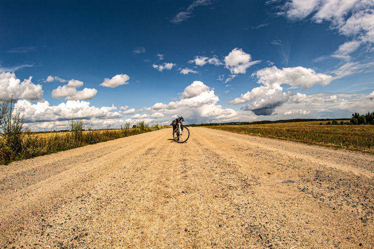 Man riding bicycle on road against sky