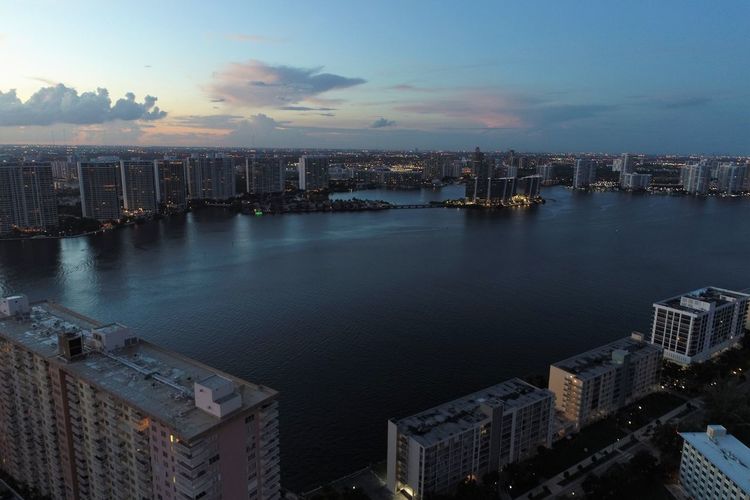 High angle view of buildings by sea against sky during sunset