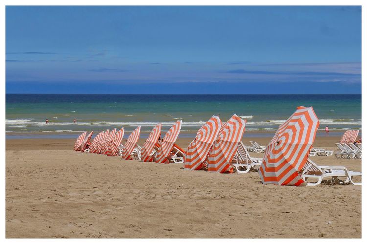 Row of parasols lying on the beach against sky. 