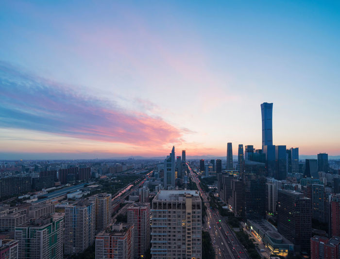 Aerial view of city buildings against sky during sunset