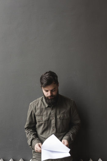 Activity Blank Book Casual Clothing Copy Space Front View Holding Indoors Lifestyles Looking One Person Paper Publication Reading Real People Studying Three Quarter Length Waist Up Wall - Building Feature Young Adult Young Men
