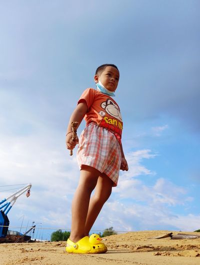 Portrait of boy standing on beach against sky