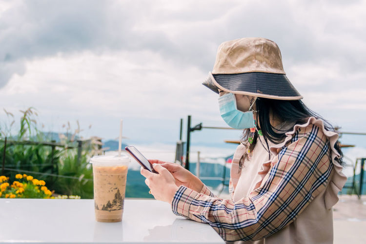Woman wearing a mask while drinking coffee while traveling