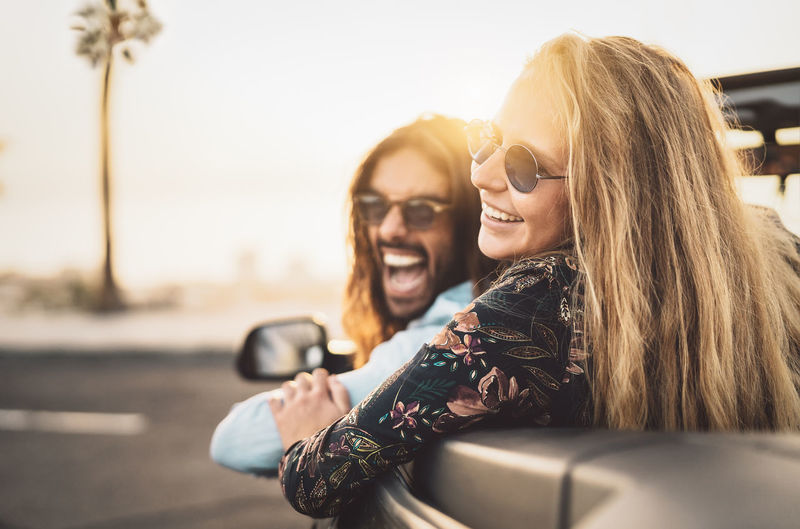 Cheerful couple wearing sunglasses traveling in convertible