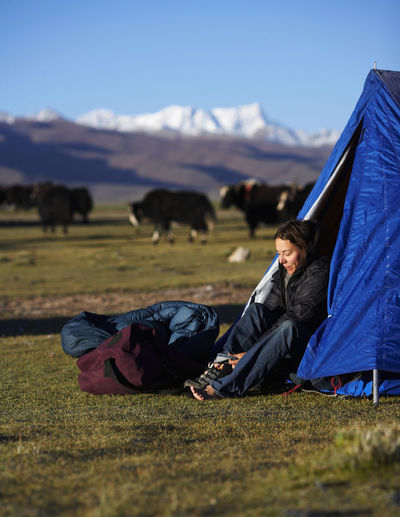 Woman putting her boots on at camp in tibet